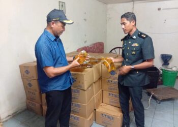 MUHAMMAD Nizam Jamaludin (kiri) memeriksa minyak masak paket bersubsidi yang dirampas dalam serbuan di sebuah premis di Kawasan Industri Ringan Kemuning di Sungai Petani.