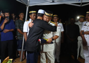 MOHD. Zawawi Abdullah (kanan) memeluk bapa arwah, Mohd. Ridzuan Md. Daud ketika menyerahkan Jalur Gemilang pada istiadat pengebumian di Tanah Perkuburan Islam Masjid Tengku Sarafudin Badlishah, Padang Terap. - UTUSAN/ SHAHIR NOORDIN