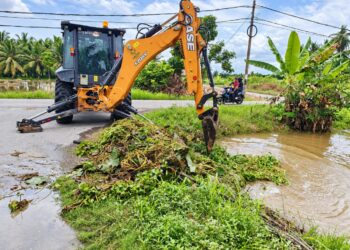 JENTERA berat digunakan untuk membersihkan tumbuhan yang menghalang aliran air di parit buang di Parit Telok Pial, Kuala Kurau hari ini.