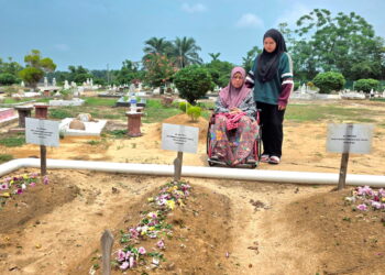 NORHAYATI Razali ditemani anaknya ketika menziarahi kubur Allahyarham suami dan dua anak di Tanah Perkuburan Islam Kampung Air Hitam Labu, Kampar, Perak.