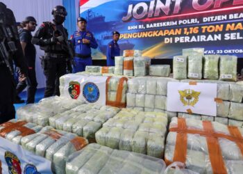 ANGGOTA polis berkawal di sisi bungkusan dadah yang dirampas pada sidang media di Belawan, Medan, wilayah Sumatera Utara. - AFP
