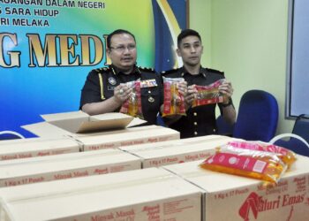 MOHD. Hazimin Jamaludin (kanan) menunjukkan minyak peket bersubsidi yang dirampas dalam sidang akhbar di Krubong, Melaka hari ini. - UTUSAN/AMRAN MULUP