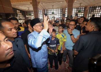 ANWAR Ibrahim menyantuni jemaah selepas hadir menunaikan solat Jumaat di Masjid Putra, Putrajaya. -UTUSAN/FAISOL MUSTAFA