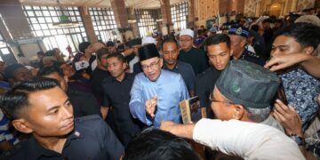 ANWAR Ibrahim menyantuni jemaah selepas hadir menunaikan solat Jumaat di Masjid Putra, Putrajaya. -UTUSAN/FAISOL MUSTAFA