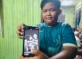 MOHD. Haziq Qoyyum Rosli menunjukkan gambar arwah (Tengah) yang maut dipercayai dipanah petir ketika ditemui di Kampung Tasek Berangan Pasir Mas Kelantan.UTUSAN/ROHANA ISMAIL.