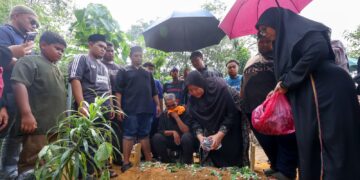 Mior Sharizal, 48 (tengah) dan isterinya, Derma Taksiah @ Norlela, 51 menabur bunga pada pusara anaknya, Derma Damiya Nur Mikayla, 7 di Tanah Perkuburan Islam Dengkil, di Putrajaya. - UTUSAN/ FAISOL MUSTAFA