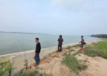 PEMANCING menunjukkan kawasan mereka terlihat buaya di Sungai Perak di Kampung Pasang Api di Bagan Datuk, Perak. – UTUSAN/AIN SAFRE BIDIN