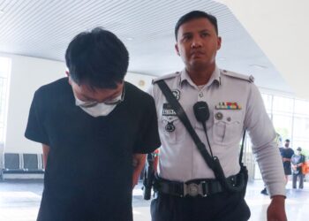 SEORANG ejen hartanah (kiri) diiringi oleh anggota polis ketika dibawa ke Mahkamah Majistret George Town, Pulau Pinang untuk mendapatkan perintah reman, hari ini.-UTUSAN/DANIAL SAAD