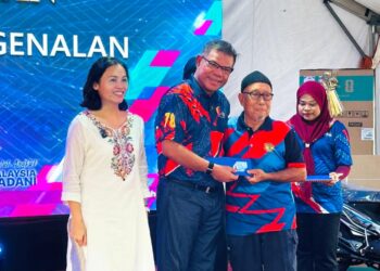 SAIFUDDIN Nasution Ismail (tengah) menyerahkan kad pengenalan generasi baharu kepada salah seorang penerima pada Program Kampung Angkat Madani di Kampung Melayu Sedenak, Kulai, Johor, semalam.