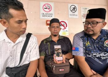 NOORWANDI A. Rahim (tengah) menunjukkan gambar anak lelakinya yang maut dalam kemalangan di Jalan Johor Bahru-Melaka, dekat Bagan, Batu Pahat, semalam.