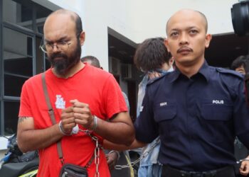S. HARI Ram (kiri) diiringi oleh anggota polis ketika dihadapkan ke Mahkamah Sesyen di sini hari ini atas pertuduhan melakukan khianat dengan api iaitu membakar sebuah kenderaan jenis Mitsubishi Xpander, Mei lalu.-UTUSAN/DANIAL SAAD