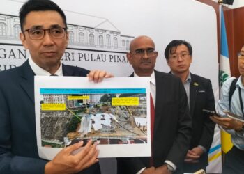 H'ng Mooi Lye (kiri) menunjukkan gambar terkini mengenai kawasan tanah runtuh di Taman Seri Rambai, Paya Terubong, George Town, Pulau Pinang.-UTUSAN/SAFINA RAMLI