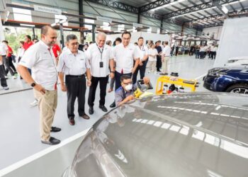 KETUA Pegawai Operasi Kumpulan DRB Hicom, Datuk Jezilee Mohamad Ramli (dua dari kiri) dan Akkbar Danial (paling kiri), melawat ruang kerja pada Majlis Pelancaran Pusat Baik Pulih Badan dan Cat EON di Kawasan Perindustrian Temasya, Glenmarie di sini semalam. UTUSAN/SHIDDIEQIIN ZON