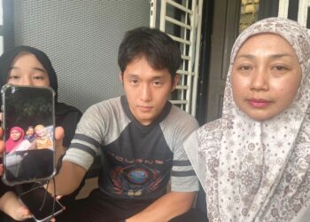 NORBANI Mahpol (kanan) dan anaknya, Daniel Aiman Low menunjukkan gambar Siti Nur Batrisya Mohd. Khalid dan Nurmaisarah Abd Jalil yang maut dalam kemalangan ketika ditemui di Kampung Parit Sagil, Ayer Hitam, Batu Pahat, Johor, semalam.
