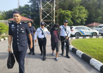 TERTUDUH semasa dibawa polis untuk prosiding pendakwaan di Mahkamah Majistret Kuala Krai, Kelantan. - UTUSAN/YATIMIN ABDULLAH