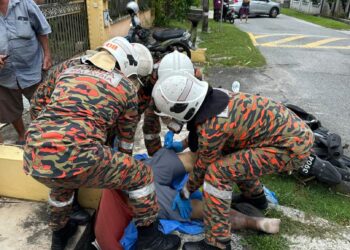 ANGGOTA bomba mengangkat mangsa selepas motosikal dinaikinya terbabas di Kampung Boyan, Taiping, hari ini. – IHSAN JBPM