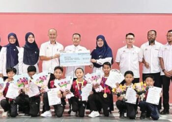 Jamalludin Baharun (tengah) memegang replika cek kemenangan bersama sebahagian guru dan jurulatih serta peserta lompat tali berirama di Sekolah Kebangsaan Temin, Jerantut, Pahang baru-baru ini. – utusan/ HARIS FADILAH AHMAD