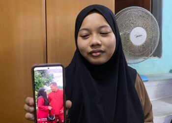 RUQAIYAH Zukifli menunjukkan gambar Allahyarham Mohamad Zulkifli Ishak dan Norshila Zali yang disimpan dalam telefon bimbit ketika ditemui di rumahnya di Kampung Pasir Era, Kuala Krai, Kelantan.