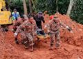 ANGGOTA pasukan penyelamat membawa keluarga mayat warga Bangladesh yang ditemukan tertimbus lebih 40 jam dalam kejadian tanah runtuh di sebuah kebun sayur di Tanah Tinggi Lojing, Gua Musang, Kelantan. - IHSAN BOMBA
