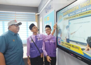 AHMAD Jailani Muhamed Yunus (kiri) mendengar penerangan pelajar mengenai penggunaan televisyen pintar yang diterima oleh SMK Simpang Beluru, Kuala Kangsar, Perak hari ini. - UTUSAN/FADZIL ZAINOL