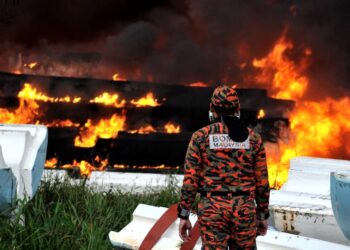 ANGGOTA bomba memantau kebakaran kawasan simpanan fiber melibatkan longgokan bongkah boya di Kampung Pasir Putih, Pasir Gudang disini. UTUSAN/RAJA JAAFAR ALI