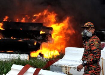 ANGGOTA bomba memantau kebakaran kawasan simpanan fiber melibatkan longgokan bongkah boya di Kampung Pasir Putih, Pasir Gudang disini. UTUSAN/RAJA JAAFAR ALI