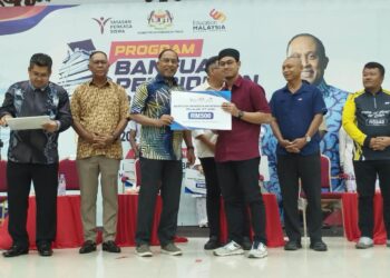 ZAMBRY Abd. Kadir (tiga dari kiri) menyerahkan replika Bantuan Pendidikan Bersasar kepada penerima dalam program di Lumut, Perak hari ini. - UTUSAN/FADZIL ZAINOL