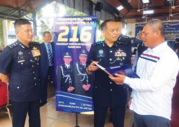 ABDUL Ghani Mohammad (kanan) melihat sijil penghargaan yang disampaikan Azman Ayob (dua dari kanan) sempena sambutan Peringatan Hari Polis Ke-216 di IPK Kelantan, semalam. - UTUSAN/ROSMIZAN RESDI.