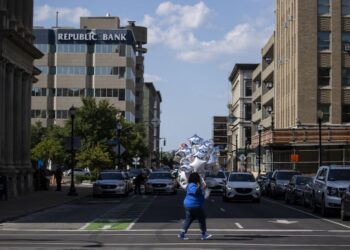 WANITA sedang melintas jalan sambil membawa belon di Louisville, Kentucky. - AFP   