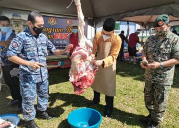 Jamaluddin Mohd. Ali (tengah) turut melapah daging korban di pekarangan Surau Markas Operasi Pasukan Polis Marin (PPMO), Lahad Datu hari ini.-IHSAN ESSCOM