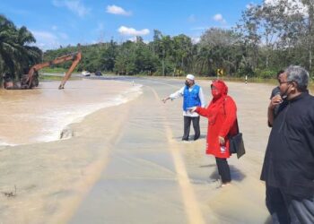 JAHAYA Ibrahim (kiri) menunjukkan air banjir yang melimpah di jalan Kampung Rantau Panjang - Unisel hari ini. - UTUSAN / ABDUL RAZAK IDRIS
