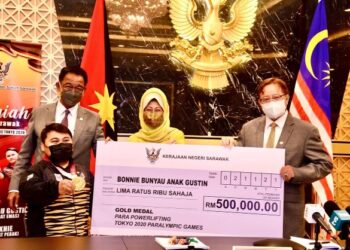 Abang Johari Tun Openg (kanan) menyampaikan cek insentif kepada Bonnie sambil diperhatikan oleh  Abdul Karim (belakang kiri) dan Fatimah Abdullah (tengah) pada majlis pemberian insentif kepada atlit paralimpik di Kuching  hari ini.