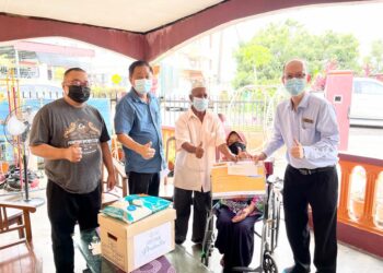 TUNG Sing Chuang (kanan) menyampaikan sumbangan bagi pengurusan jenazah kepada Salimah Surep (berkerusi roda) di rumahnya di Rumah Murah Pekan Nanas, Pontian, Johor, baru-baru ini.