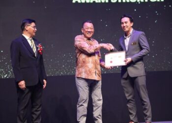 BUNG Moktar Radin (tengah) menyampaikan Anugerah Perkhidmatan Cemerlang kepada salah seorang kakitangan JKR Sabah di Kota Kinabalu semalam.