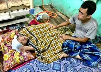 TUAN Fazlee Tuan Losing menemani Siti Khatijah Pak Man di rumah mereka di Kampung Jal Kechik, Tumpat, Kelantan. - UTUSAN/ FOTO ROSLIZA MOHAMED