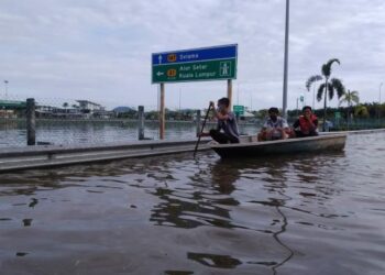 TIGA remaja menaiki sampan ketika melalui jalan berhampiran Plaza Tol Alor Pongsu yang dinaiki air dekat Bagan Serai hari ini. - UTUSAN/WAT KAMAL ABAS