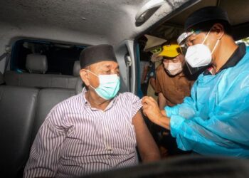 HAJIJI Noor (tengah) menyaksikan seorang warga emas menerima vaksin di PPV Hospital Tuaran hari ini