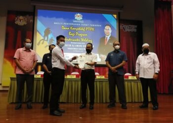 AWANG Hashim (tengah) menyerahkan surat tawaran dana kompetitif PTPK kepada seorang peserta program kimpalan bawah air di Pusat Latihan Teknologi Tinggi (Adtec) Kemaman di Kemaman, hari ini. - NIK NUR IZZATUL HAZWANI NIK ADNAN