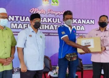 AWANG Hashim (kanan) menyampaikan sumbangan kepada seorang pesawah pada Majlis Penyerahan Bakul Makanan Kementerian Pertanian dan Industri Makanan (MAFI) Prihatin MADA di Pertubuhan Peladang Kawasan (PPK) MADA D-III, Titi Haji Idris, Pendang hari ini.