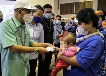 MAXIMUS Ongkili (kiri) menyampaikan Bantuan Wang Ihsan kepada mangsa banjir di Dewan Komuniti Kota Marudu semalam.