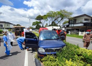 ANGGOTA  penyelamat  mengeluarkan mangsa dari kenderaan yang dipandu mangsa.