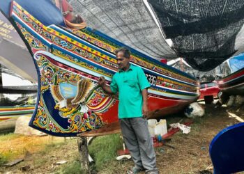 PAK Nan menunjukkan lukisan burung diukirnya pada perahu kolek milik nelayan di Kampung Pulau Gajah, Sabak, Kota Bharu. - UTUSAN/ROSLIZA MOHAMED