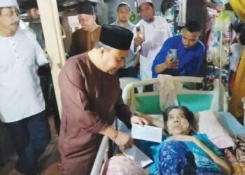 MUSTAPA Long (tengah) menyampaikan cek bantuan kerajaan negeri bernilai RM5,000 kepada Faridah Ishak yang menderita penyakit strok di Kampung Sentang di Lipis, Pahang. - UTUSAN/HARIS FADILAH AHMAD