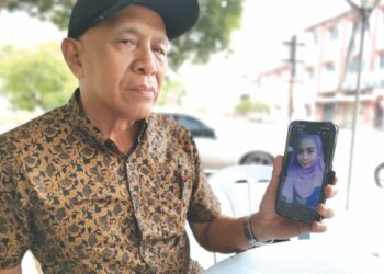 YAHYA Ahmad menunjukkan gambar Nuremalina yang menghilangkan diri sejak setahun lalu di Kampung Sungai Galah, Kampung Gajah di Pasir Salak, Perak. - UTUSAN/AIN SAFRE BIDIN