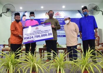 ABDUL RAHMAN Mohamad (tengah) menyampaikan replika cek bernilai RM24,786 juta kepada Mat Roni Zakaria (kiri) bagi peruntukan pembangunan sosial dan modal insan di Pahang sempena Majlis Iftar Ramadan Warga Felcra Kawasan Sungai Temau, Padang Tengku di Lipis, Pahang. - UTUSAN/HARIS FADILAH AHMAD