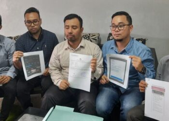 PEGUAM Febi Irianto (baju putih) menunjukkan laporan polis yang dibuat seorang doktor selepas ditipu ulat tiket yang kononnya menjual tiket konsert Coldplay. - AGENSI