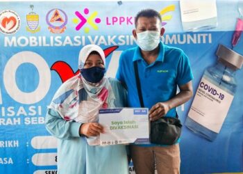 SARINA Ayub (kiri) dan suaminya, Mohd. Ali Zawawi berkongsi pengalaman divaksin dalam bas semasa hadir pada program PPV Bergerak Guar Jering, Bukit Mertajam, Pulau Pinang.