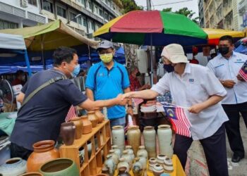 CHRISTINA Liew (dua kanan) mengagihkan bendera Jalur Gemilang kepada peniaga di Tamu Jalan Gaya di Kota Kinabalu semalam.