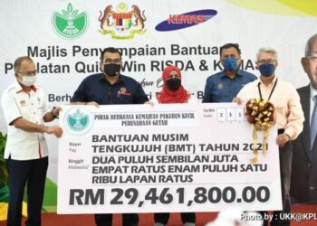 Hasbi Habibolllah (dua dari kiri) menyempurnakan simbolik penyerahan bantuan musim tengkujuh di Kuching semalam