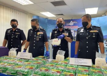 ABDUL MAJID Mohd. Ali (dua, kanan) menunjukkan bungkusan dadah yang dirampas dalam serbuan di sebuah rumah inap desa, di Melaka, minggu lalu.